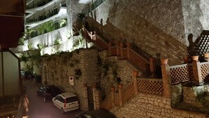 Ein Nachtblick auf eine Straße mit einer Steinmauer, einer Treppe und geparkten Autos.