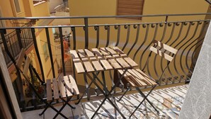 Ein Balkon mit Metallgeländer, einem Holztisch und einem Klappstuhl.