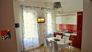 Eine moderne Küche mit roten Schränken, einer weißen Arbeitsplatte und einem Essbereich mit Tisch und Stühlen.