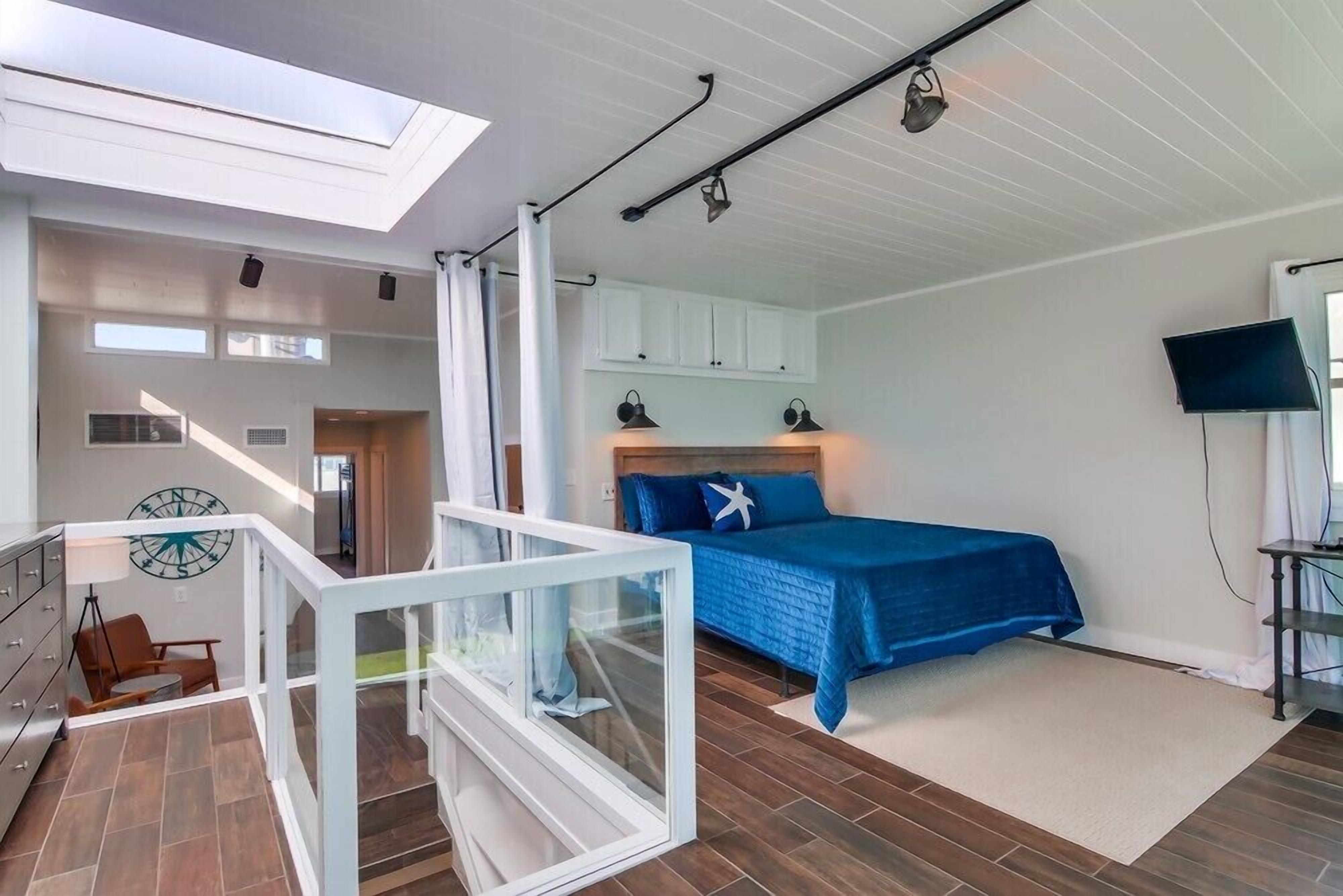 Une chambre à coucher avec un lit, un téléviseur et un escalier menant à un étage supérieur.