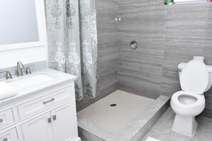 A modern bathroom with a shower, toilet, and vanity. - Island Turquoise Rental (Providenciales)