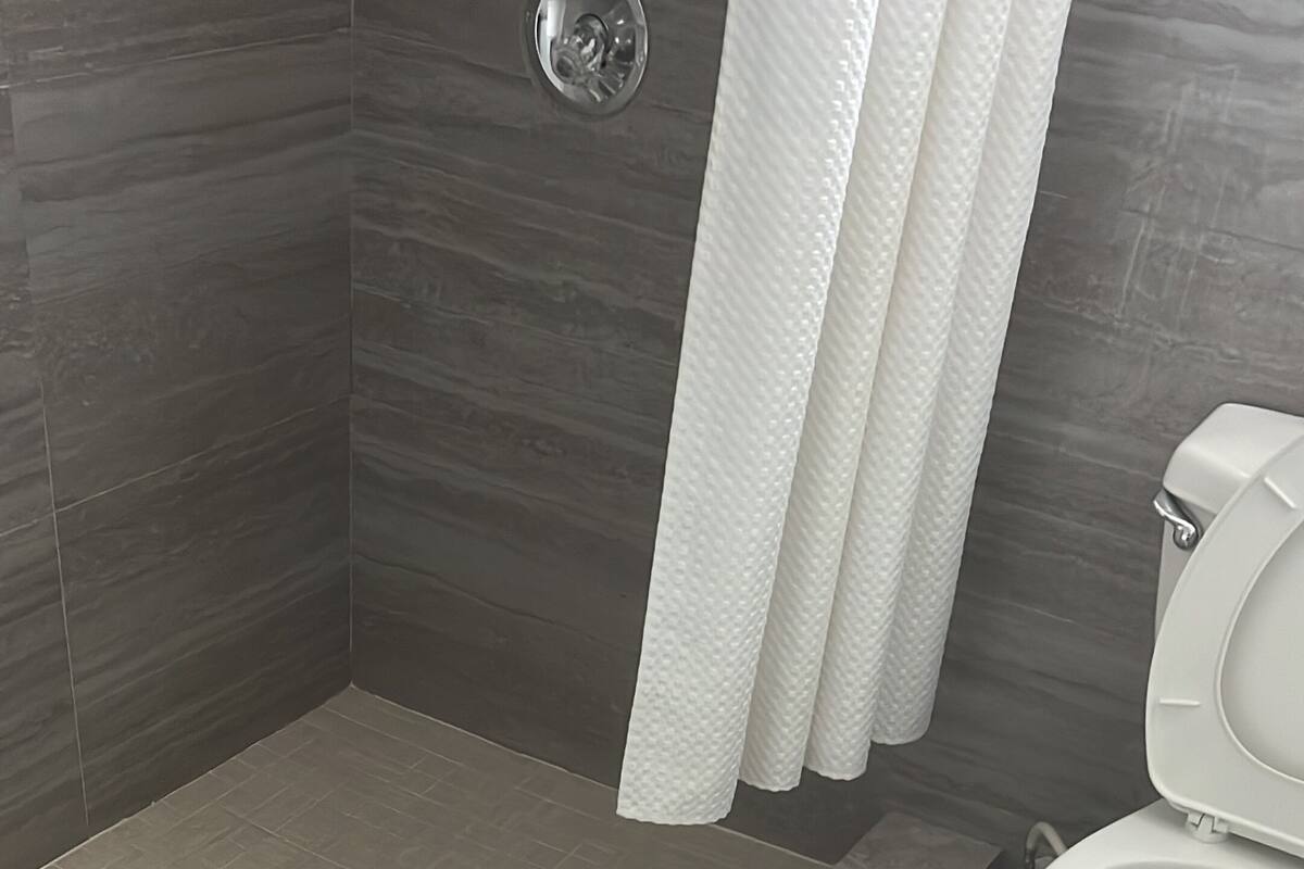 Ein Badezimmer mit Dusche, Toilette und einer grünen Fußmatte.