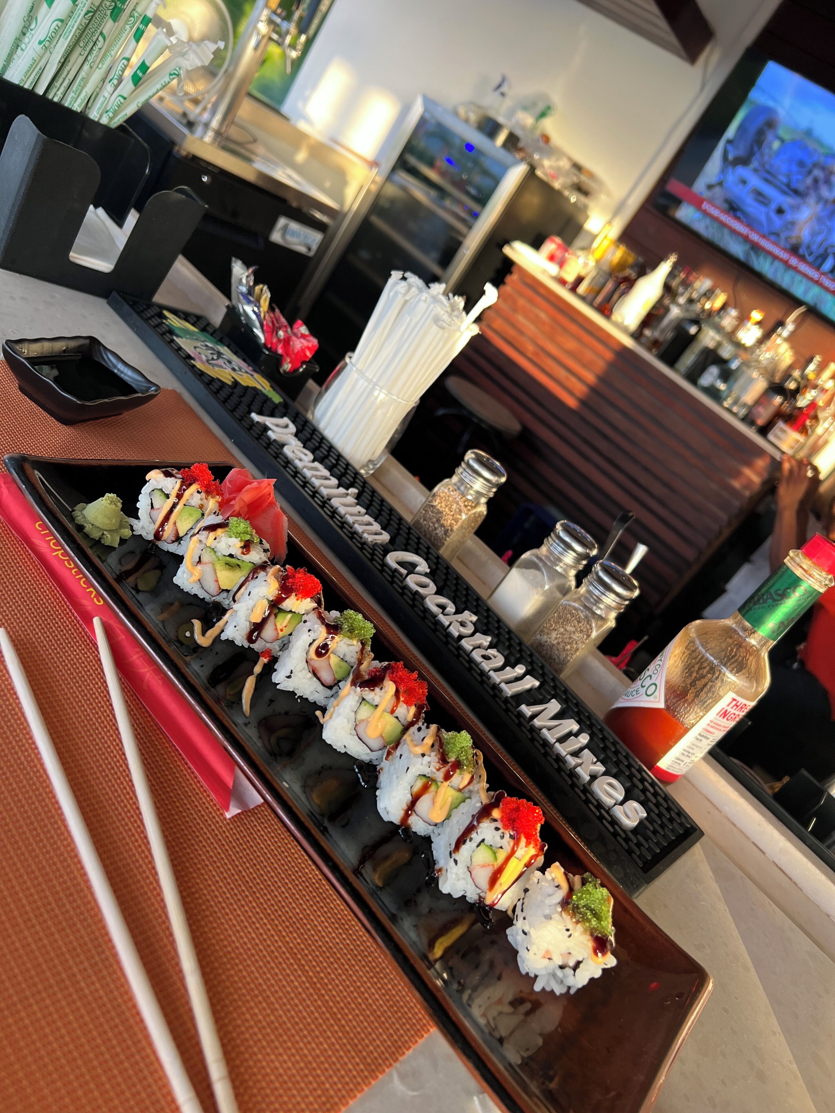 Een sushi bar met diverse sushirollen en een cocktailkaart.