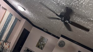 Een kamer met een plafondventilator, een klok, een schilderij en een witte toonbank.