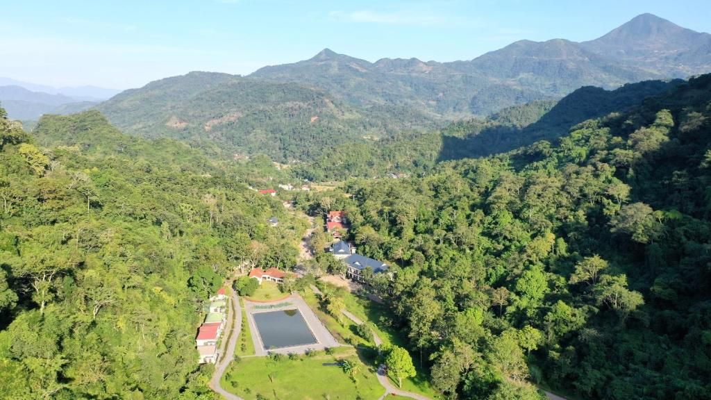 Paisagem montanhosa com um pequeno conjunto de edifícios cercados por floresta densa.