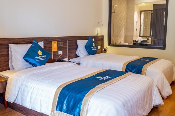 A hotel room with two beds, each with a blue and white bedspread and matching pillows.