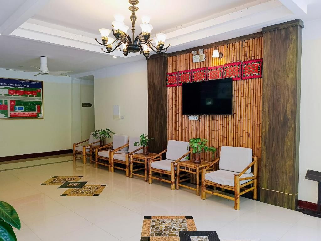 A lobby with a reception desk, a flat-screen TV mounted on a bamboo wall, and a row of wicker chairs.