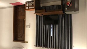 Una habitación con puerta de madera, estante empotrado, televisión de pantalla plana y refrigerador.
