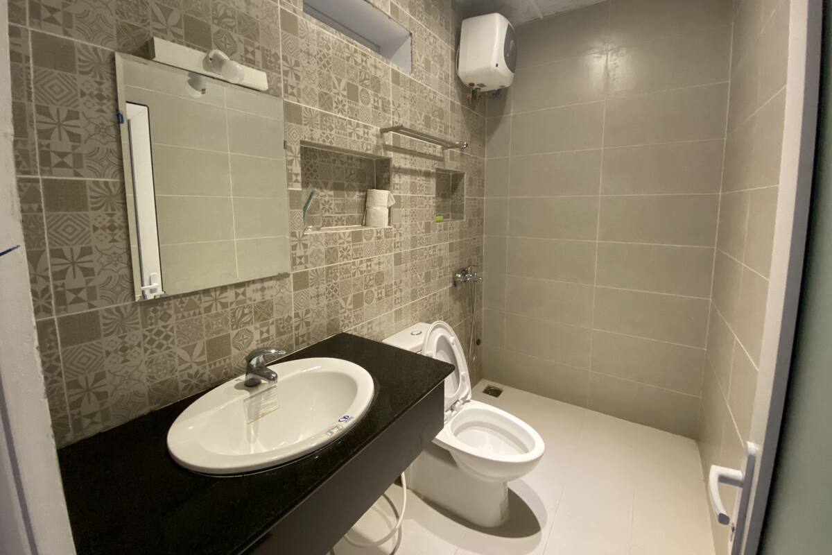 A bathroom with patterned tiles, a sink, a toilet, and a mirror.