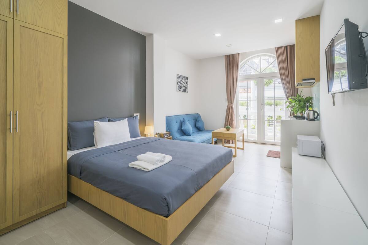 Een moderne slaapkamer met een groot bed, een blauwe bank, een televisie en uitzicht op de omgeving.