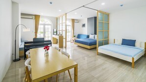 Une pièce moderne et bien éclairée, comprenant une table à manger, un canapé et un lit.