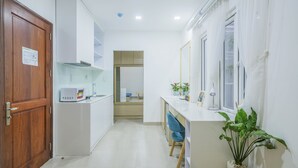 Une cuisine moderne avec des armoires blanches, un four à micro-ondes et une chaise bleue.