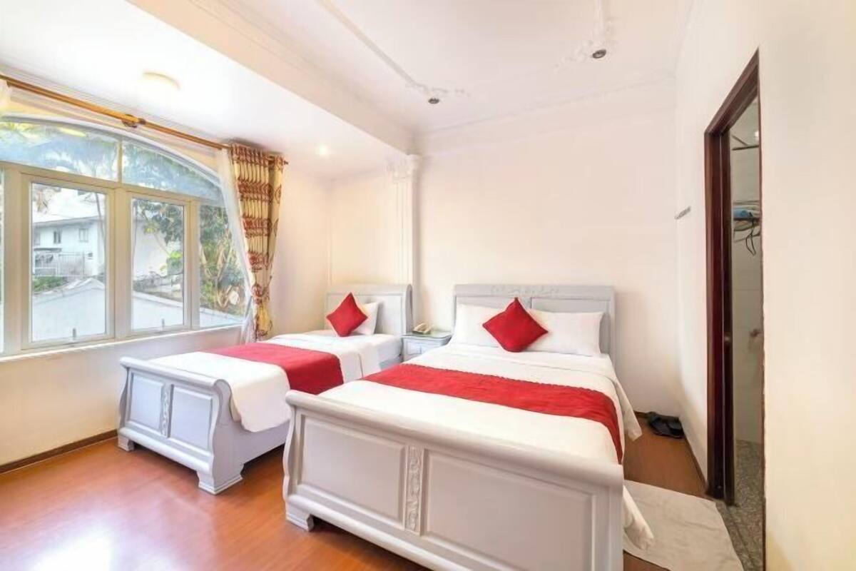 A hotel room with two beds, a large window, and a view of the street.