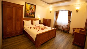 A spacious bedroom with a large wooden bed, a wooden wardrobe, a small wooden table, and a chair. - Dragon King 1 Hotel Da Lat (Xuan Huong - Da Lat)