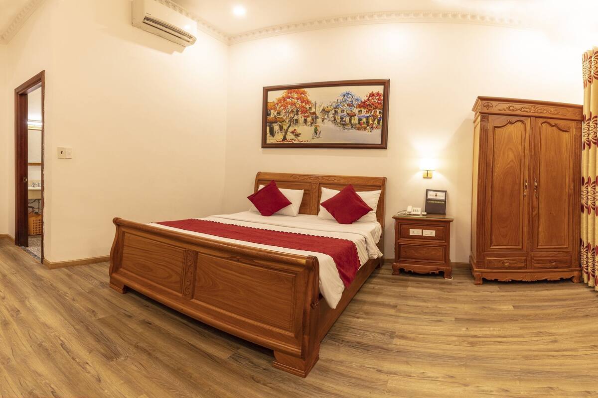 A bedroom with a wooden bed, a nightstand, a wardrobe, and a painting on the wall.