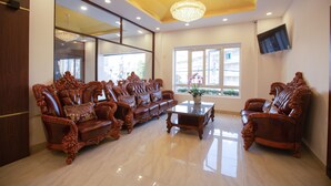 A spacious living room with ornate wooden furniture, a chandelier, a large mirror, and a television mounted on the wall. - Dragon King 1 Hotel Da Lat (Xuan Huong - Da Lat)