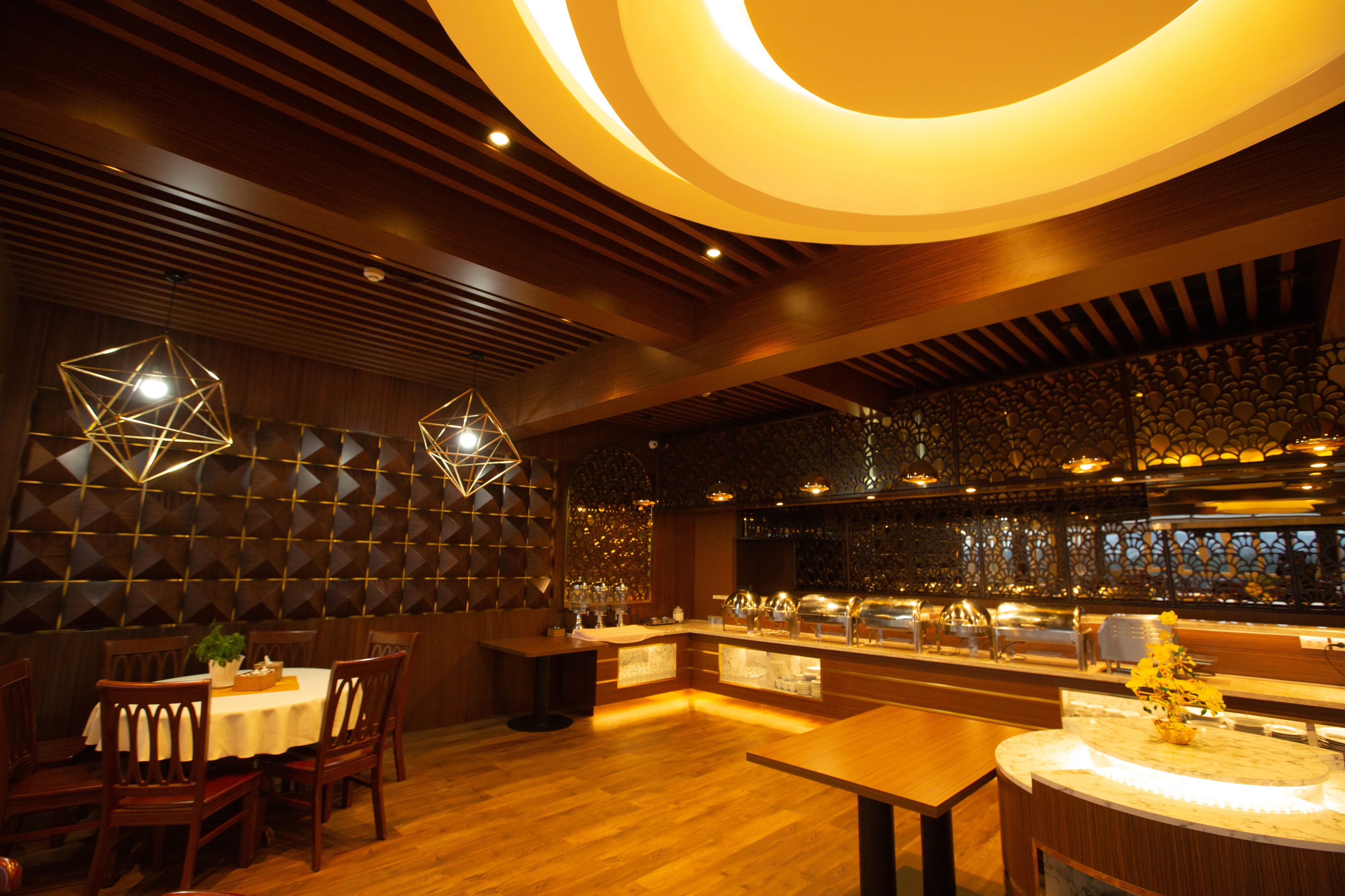 A restaurant with wooden flooring, a bar area, and geometric light fixtures.