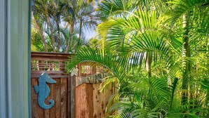 A tropical garden with a wooden gate, palm trees, and a stone pathway.