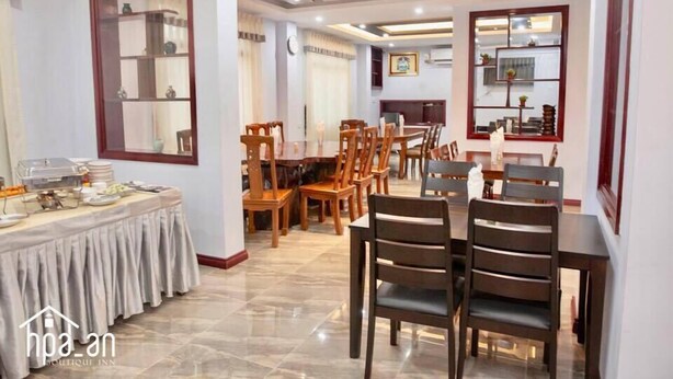 A hotel dining area with multiple tables and chairs, a buffet setup, and a large mirror on the wall. - Hpa An Boutique Inn (Hpa-An)