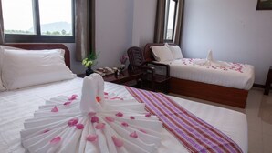 A hotel room with two beds, a wooden desk, and a view of the outdoors. - Hpa An Boutique Inn (Hpa-An)