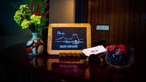 A wooden sign with a chalkboard background and a graph, a vase with flowers, and a glass bowl with flowers on a table. - Hpa An Boutique Inn (Hpa-An)