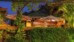 A restaurant with outdoor seating, covered by umbrellas, surrounded by lush greenery. - Rikitikitavi (Kampot)