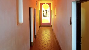 A hallway with a tiled floor leading to a door with a sign that reads "RIKI TAVI". - Rikitikitavi (Kampot)