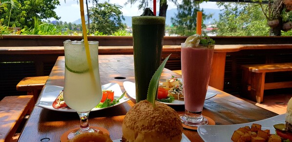 A table with three drinks, a burger, and a plate of food. - Rikitikitavi (Kampot)