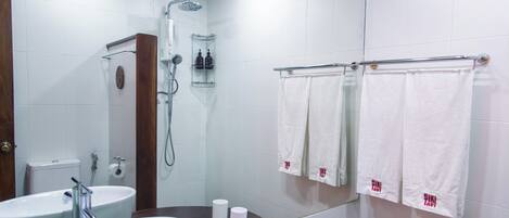 A modern bathroom with two sinks, a shower, and a towel rack with towels.