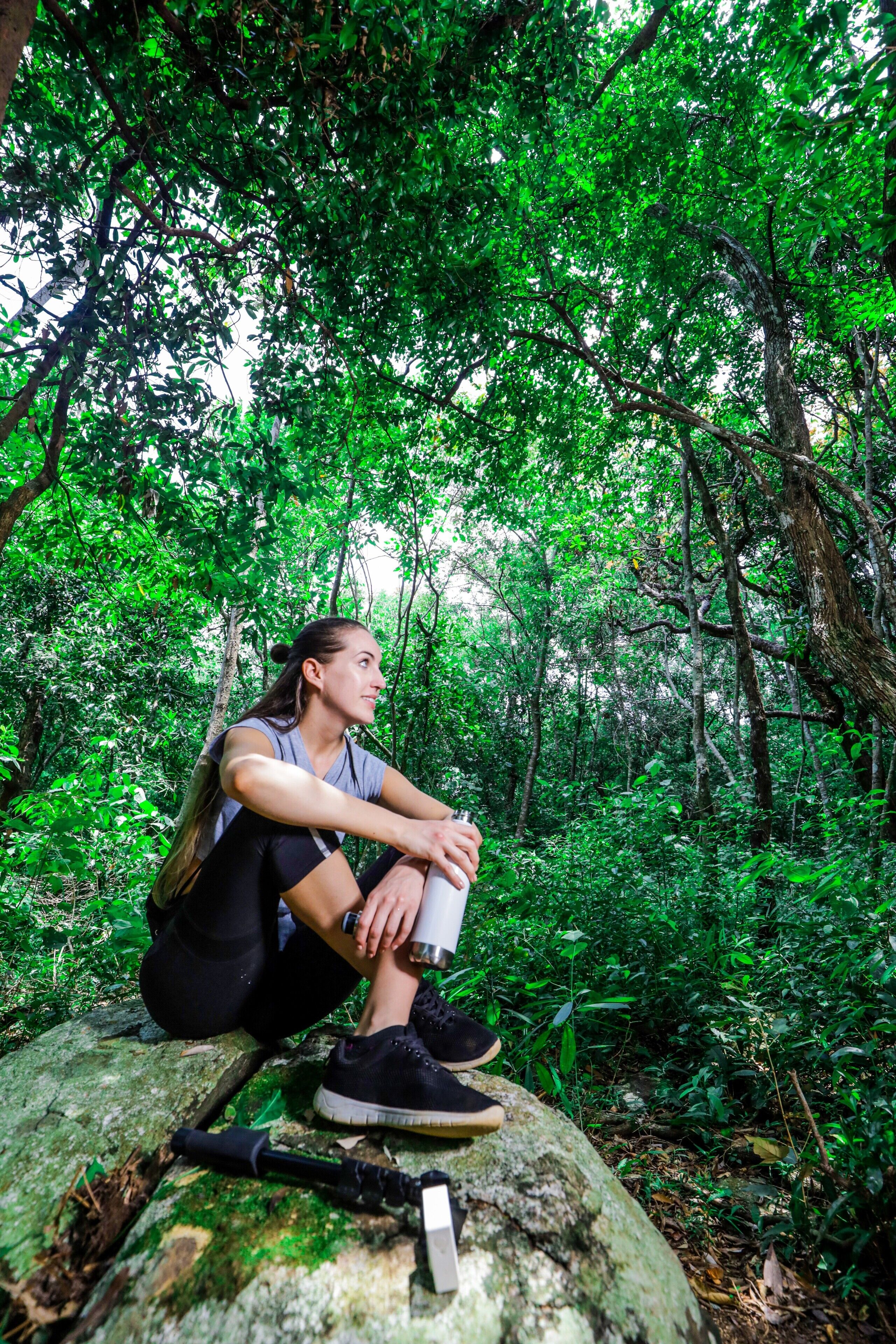 A person sitting on a rock in a forested area.