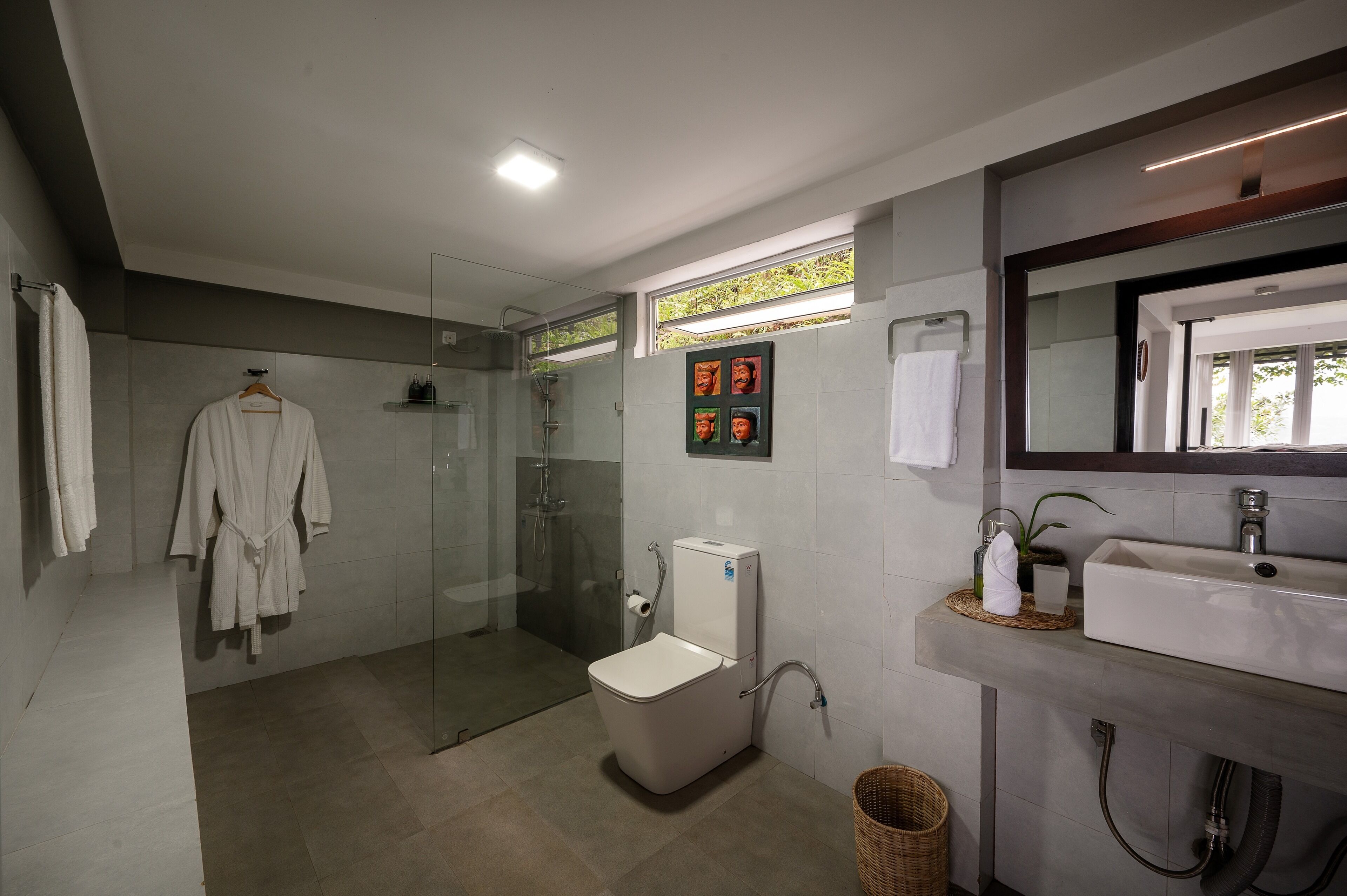 A modern bathroom with a glass-enclosed shower, a toilet, and a sink.