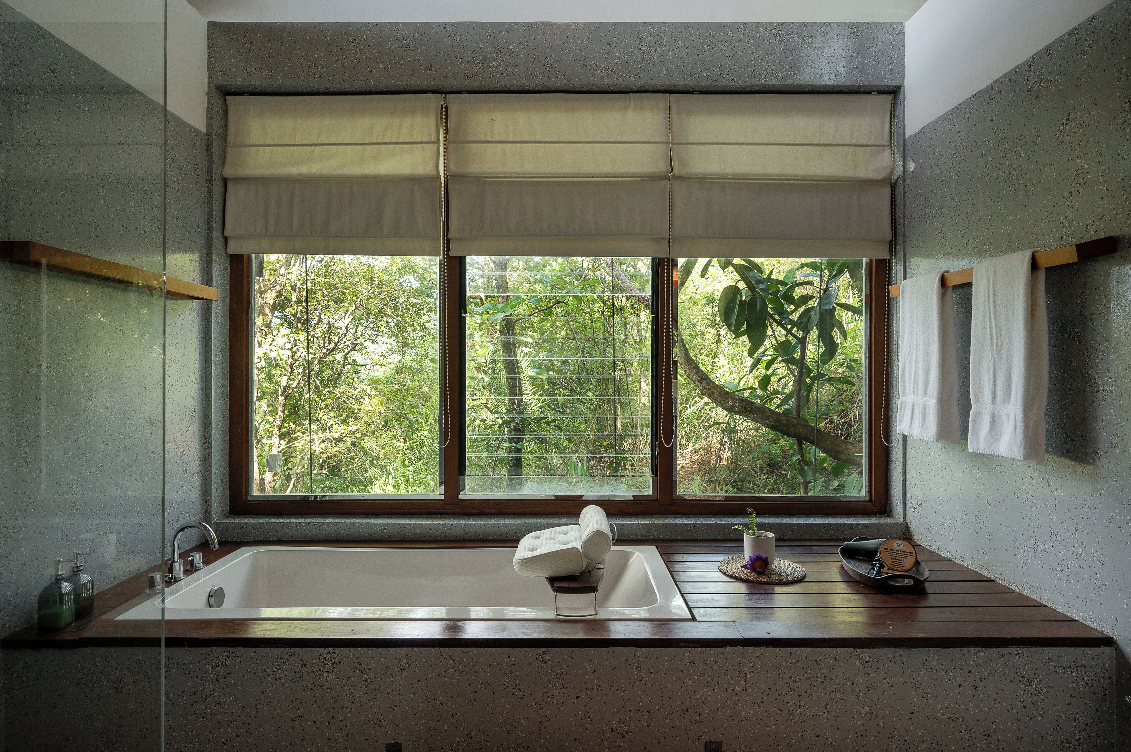 A bathroom with a large window, a bathtub, a sink, and a towel rack.