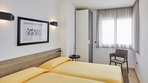 A hotel room with two beds, a framed picture on the wall, a chair, and a window with curtains. - APARTMENT (5 ADULTS ) POOL VIEW (L'Estartit)