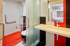 A modern bathroom with a glass shower enclosure, a white sink, and a red accent wall. - APARTMENT (5 ADULTS ) POOL VIEW (L'Estartit)
