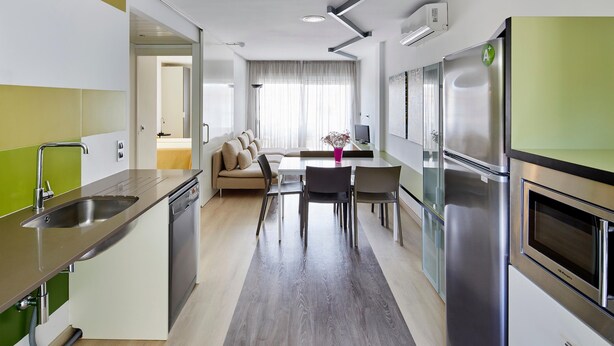 A modern kitchen with a built-in dishwasher, a stainless steel refrigerator, and a dining area with a table and chairs. - APARTMENT (5 ADULTS ) POOL VIEW (L'Estartit)