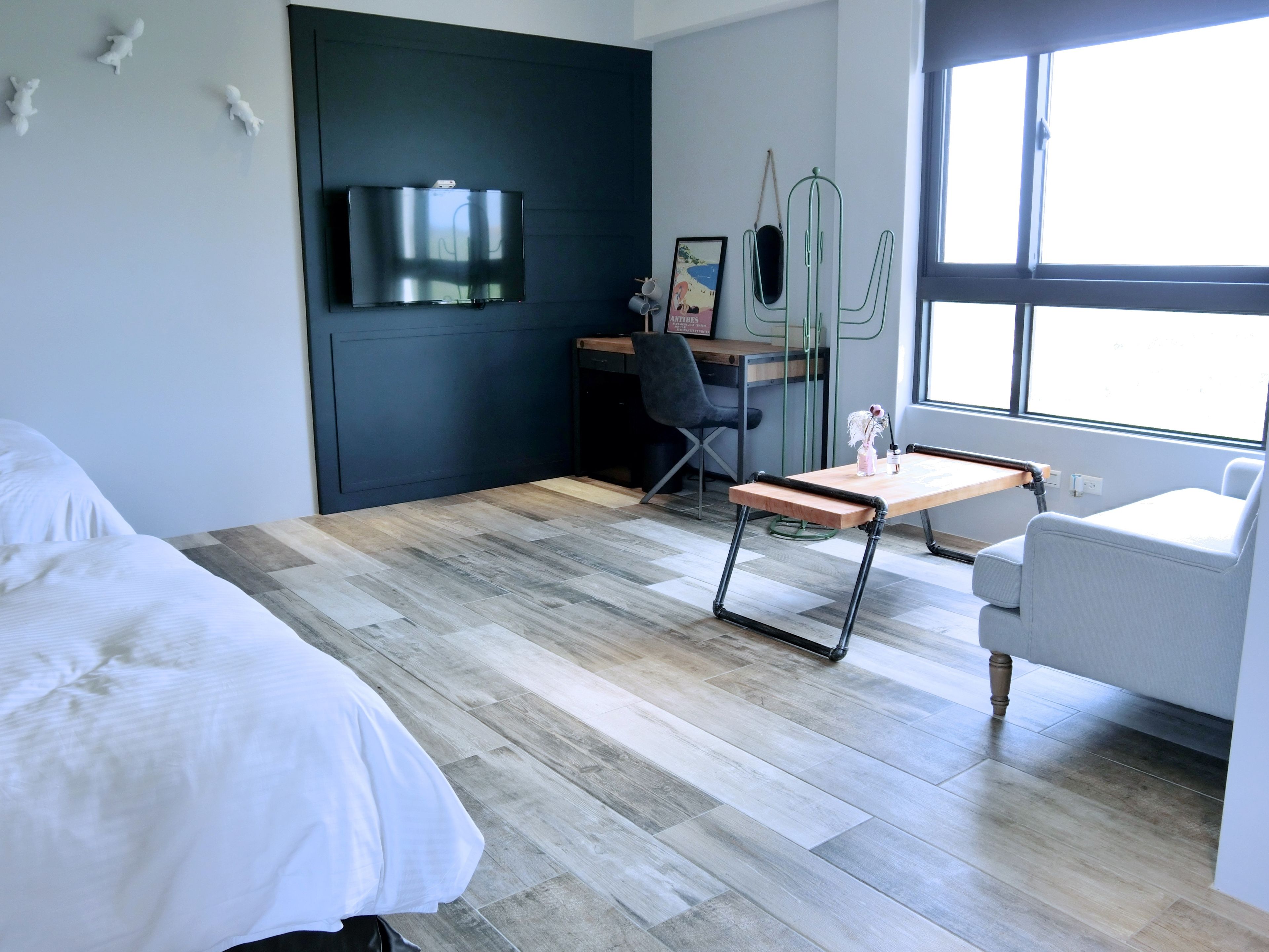 A modern hotel room with a bed, a desk, a chair, and a window.