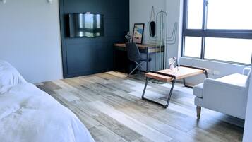 A modern hotel room with a bed, a desk, a chair, and a window.
