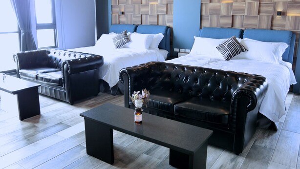 Habitación de hotel con dos camas, un sofá, una mesa de centro y vistas a la ciudad.