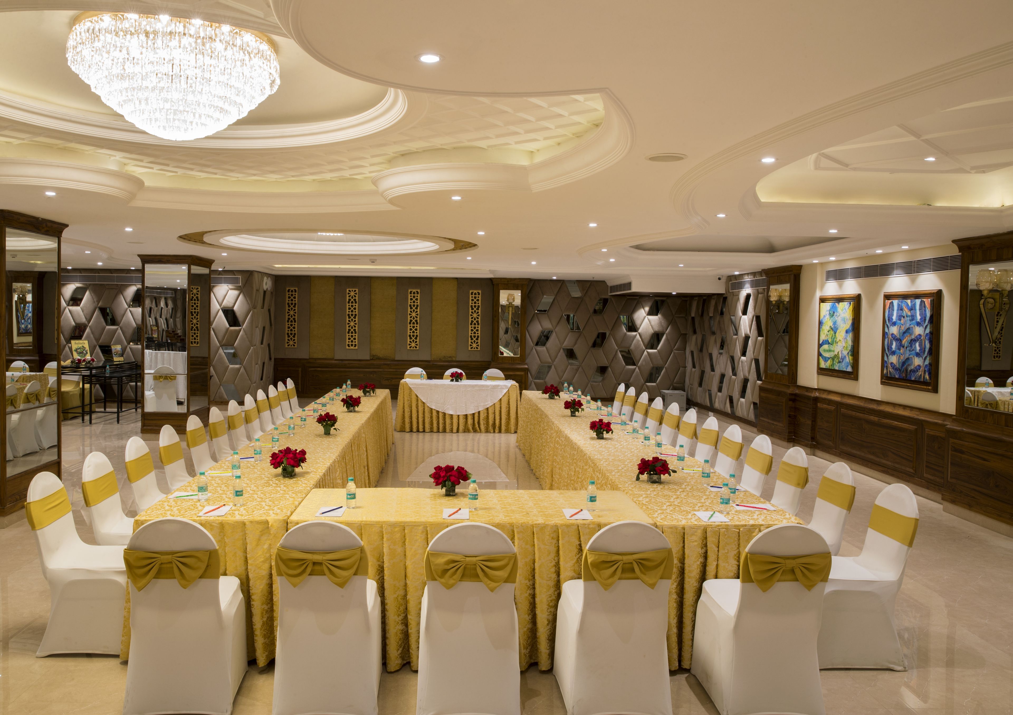 A conference room with a long table, white chairs with gold sashes, and a chandelier.