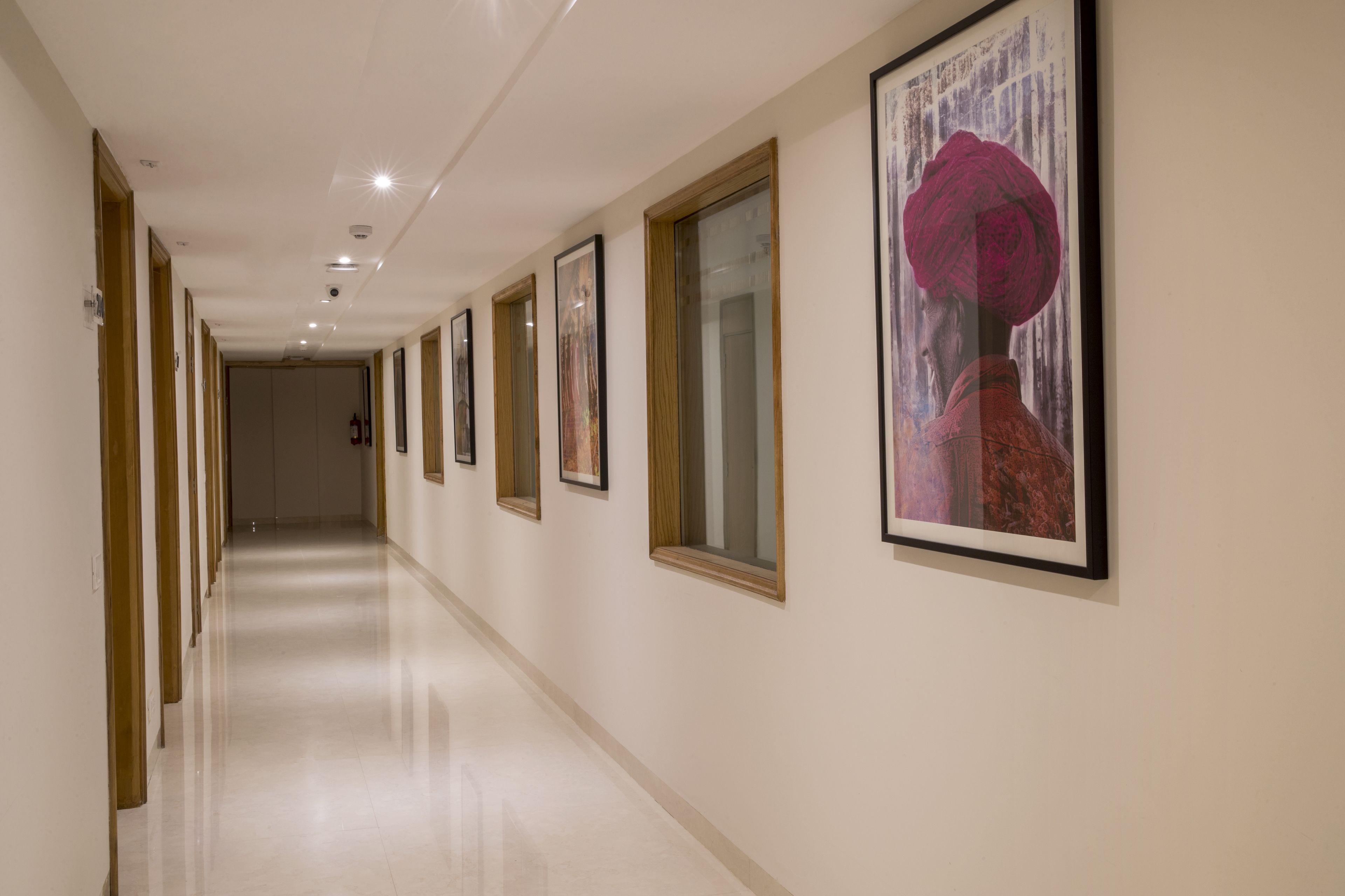 A long, well-lit hallway with framed artwork on the walls and a polished floor.