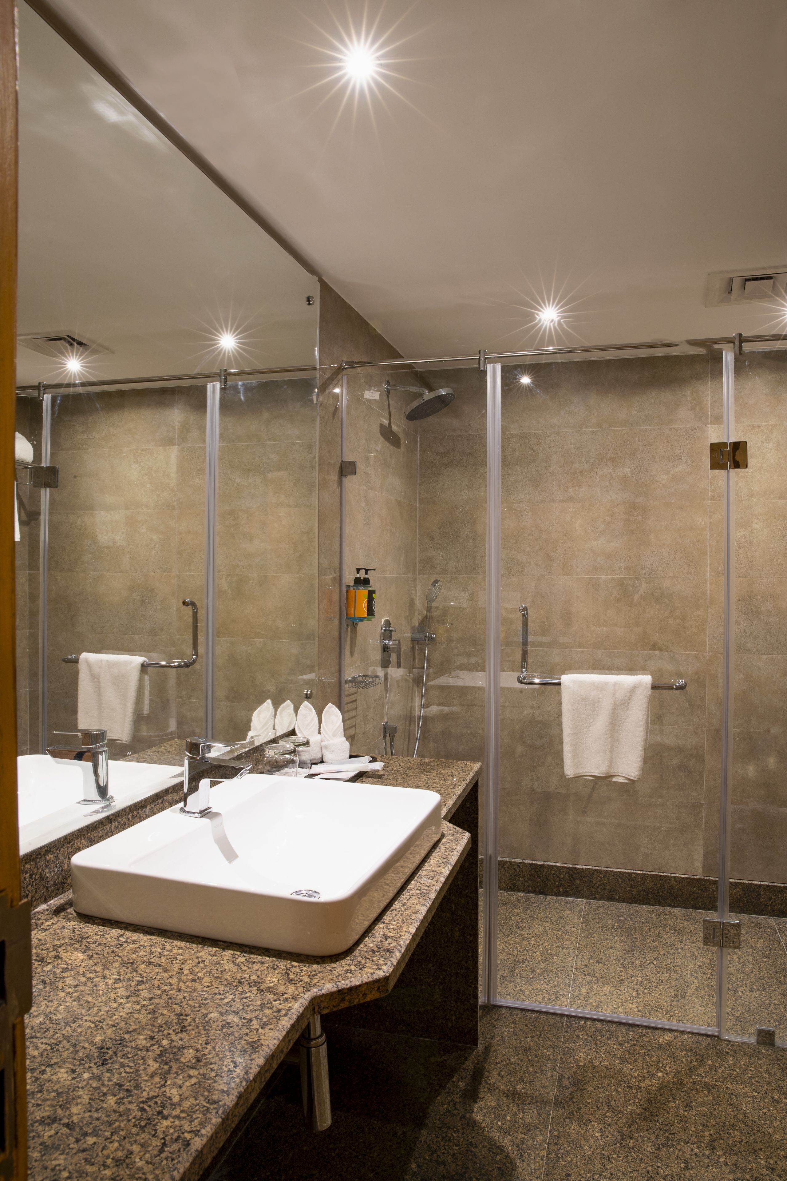 Un baño moderno con un lavamanos grande, cabina de ducha con mampara de vidrio y un espejo.