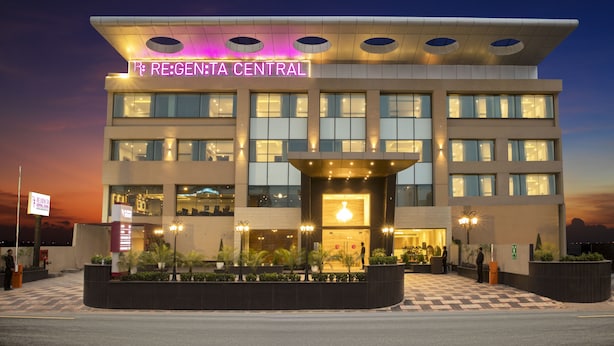 Un hotel moderno con entrada central, varios pisos y una fachada bien iluminada.
