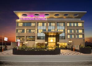 A modern hotel with a central entrance, multiple floors, and a well-lit facade. - Regenta Central Cassia Zirakpur Chandigarh (Dera Bassi)
