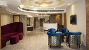 Un lobby moderno con un sofá rojo curvado, sillones azules y un mostrador de recepción.
