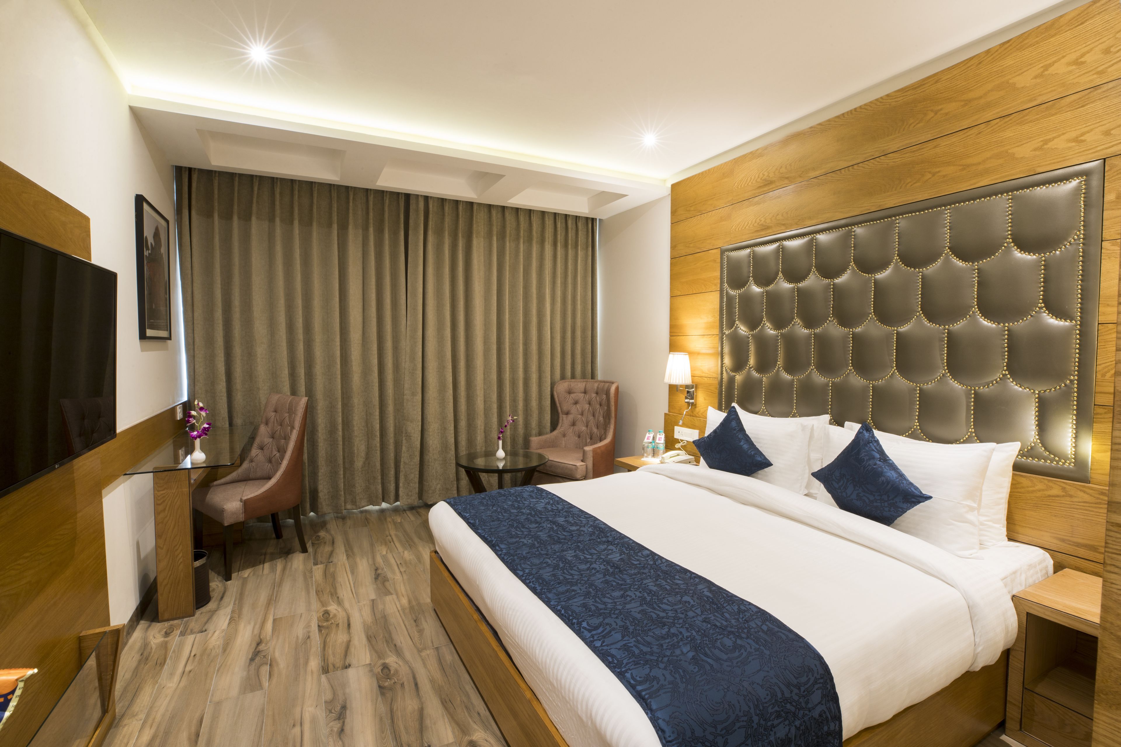 A hotel room with a large bed, a flat-screen TV, a desk, and a chair.
