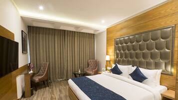 A hotel room with a large bed, a flat-screen TV, a desk, and a chair.