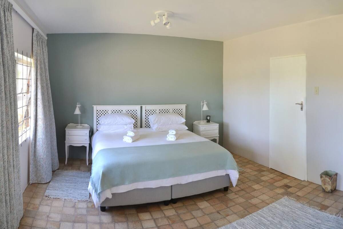 A neatly arranged bedroom with a bed, bedside tables, and a door.