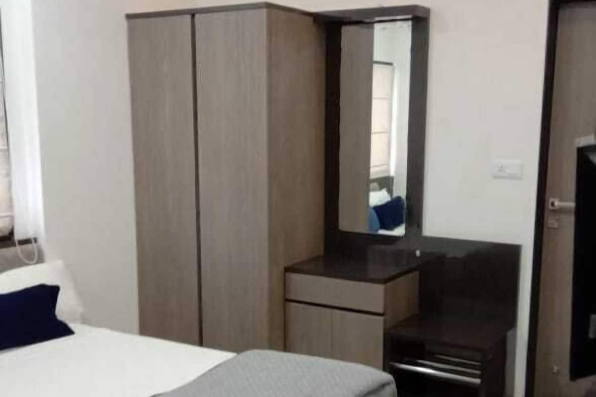 A modern hotel room with a bed, wardrobe, vanity, and a television.