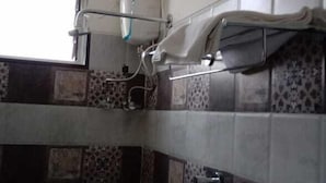 Un baño con pared de azulejos, un perchero y un sistema de ventilación.
