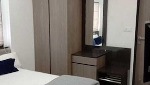 Una habitación de hotel moderna con una cama, un armario, un escritorio y un televisor.